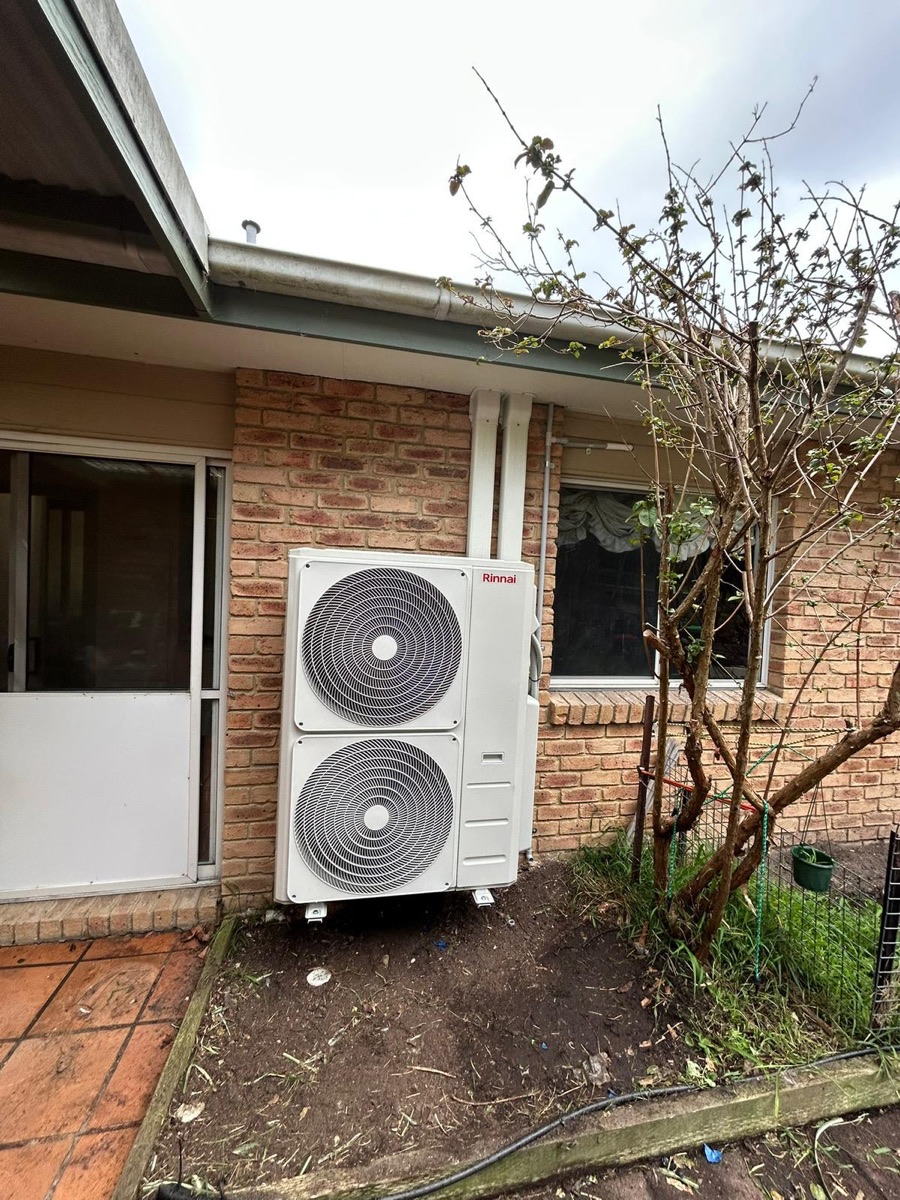 Twin-fan outdoor condenser unit installed beside a home