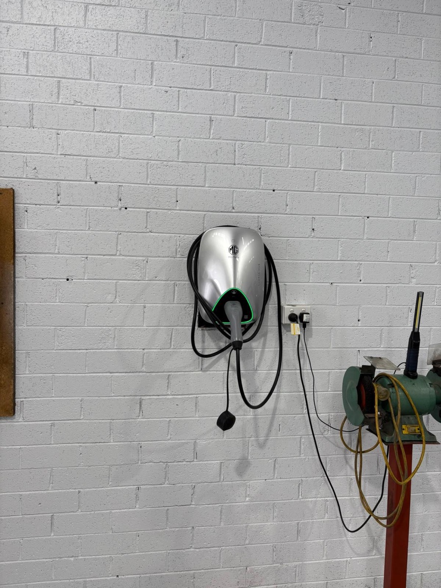 Wall-mounted EV charger installed on a workshop brick wall